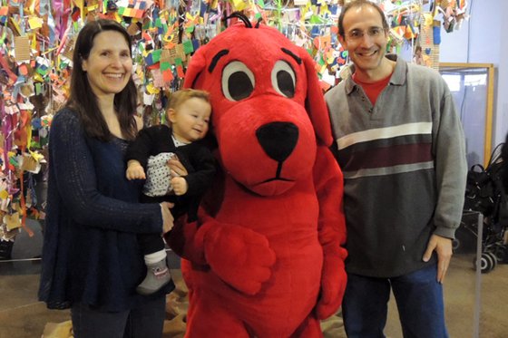 Family standing next to Clifford the Big Red Dog. 