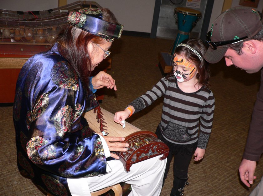 Child learning about Tet cultural from adult dressed in traditional attire. 