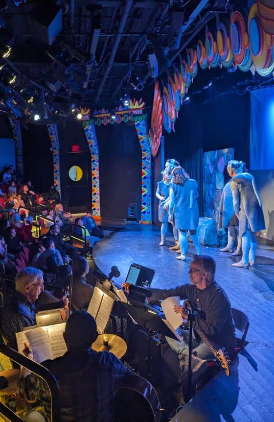 LICM's theater stage featuring actors dressed as mice and with visitors in the audience with the pit band in the foreground. 