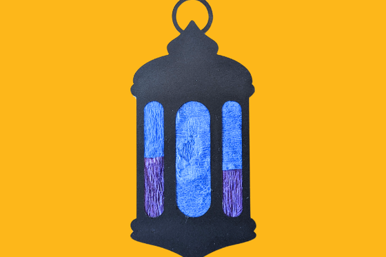 A black lantern with blue and purple tissue paper as windows. 