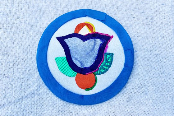 Fabric applique medallion of a tulip in hues of blue.
