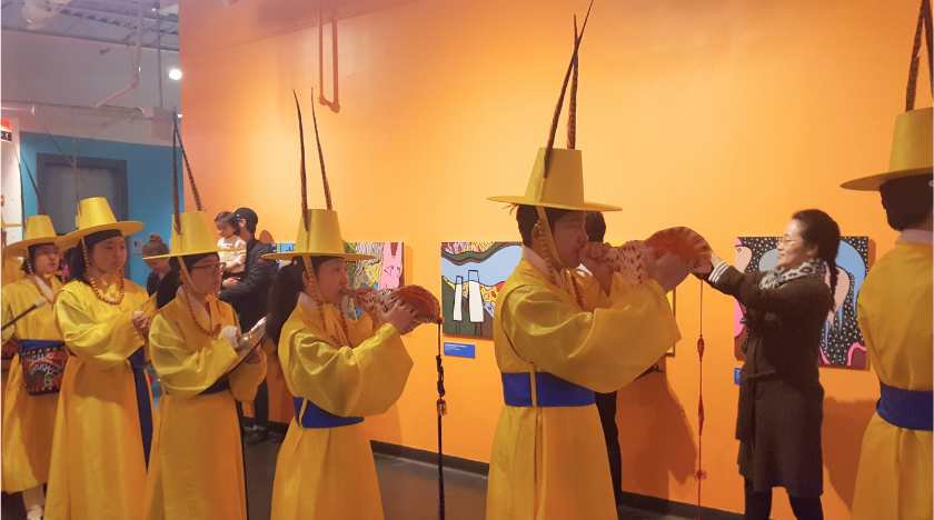 A Korean marching band playing instruments in a line wearing traditional clothing. 
