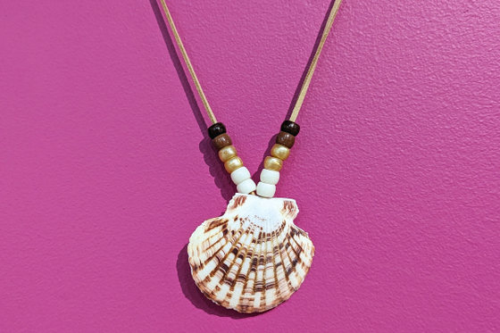 A leather necklace decorated with a shell, and earth-toned beads. 