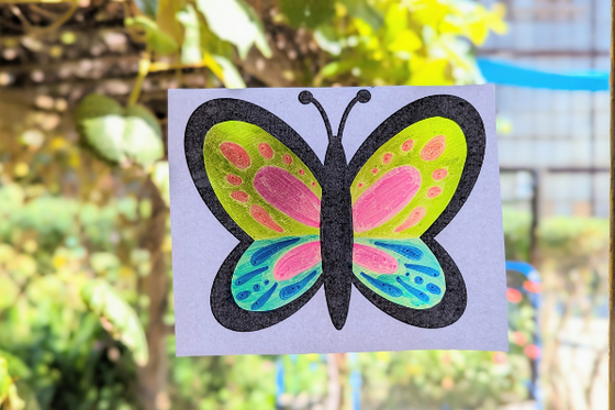A graphic of a butterfly on clear paper colored with markers. 