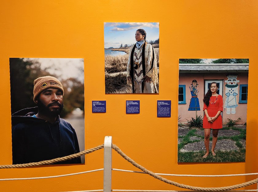 Photograph of a wall containing three printed photos of indigenous people. 