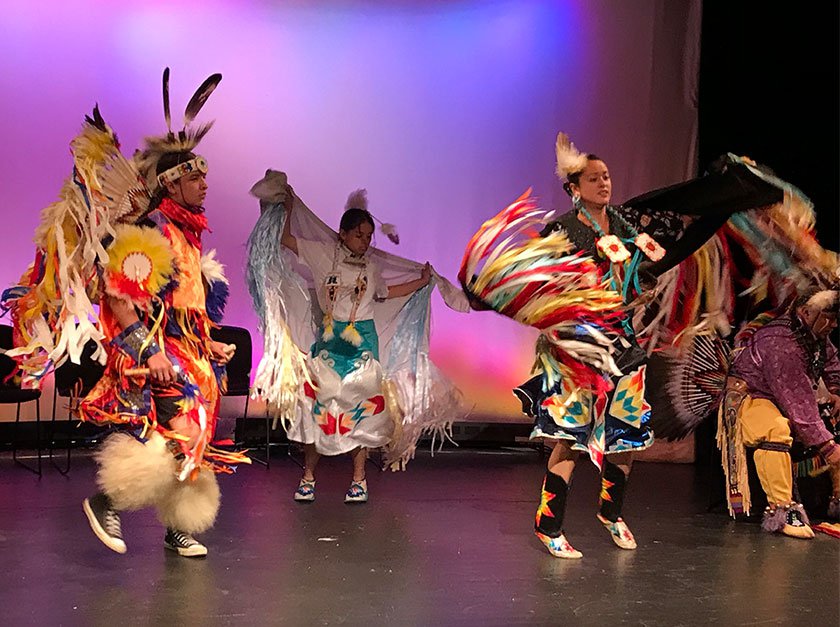 Photo of indigenous performers on stage in traditional clothing.