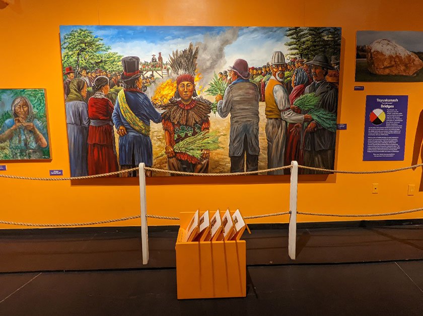 Photograph of a wall containing paintings within the Toyuskanash exhibit. 