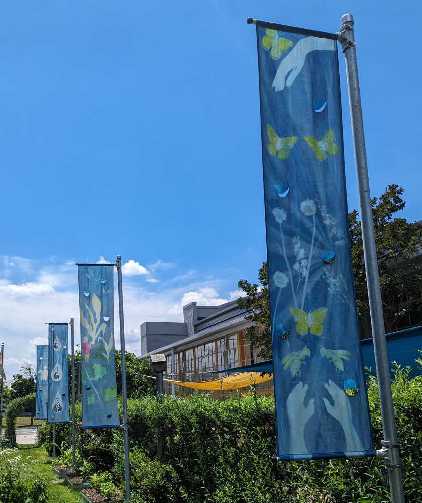 Five blue paintings featruing nature on silks hanging in LICM backyard. 