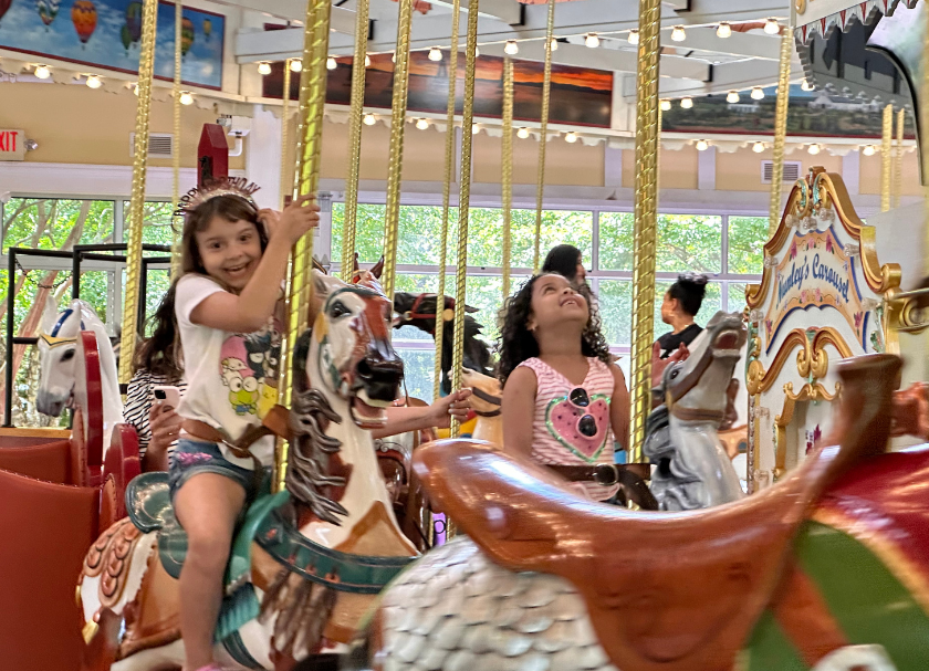 Two children looking at the camera smiling while riding Nunley's Carousel. 