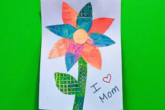 A flower made with collaged petals and stem and I heart mom. 