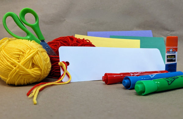 Yellow and red yarn, markers, a white bookmark, a glue stick and colored construction paper. 