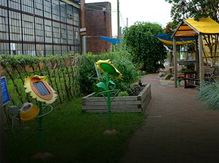 Our Backyard exhibit at LICM featuring two large metal sunflowers, a planter box and a brick pathway. 